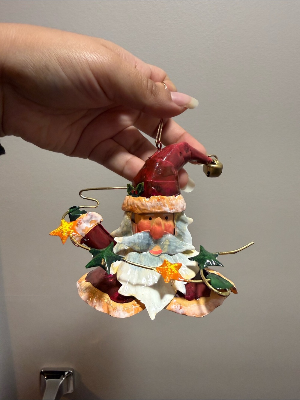 Whimsical Santa face ornament with a red hat and gold bell
